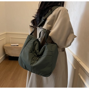 Détail d'un grand sac fourre-tout en nylon vert foncé avec de larges bretelles sur un modèle