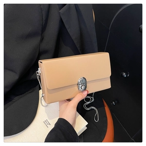Close-up of khaki rectangular crossbody bag with silver metal lock and chain strap