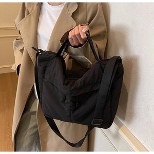 Détail d'un sac bandoulière en nylon noir avec sangle large et design minimaliste