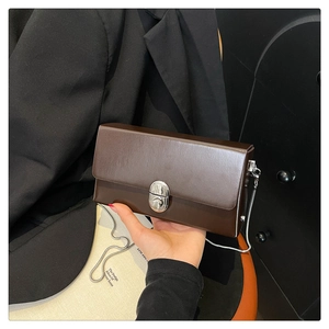 Detailed view of dark brown leather chain bag with a silver metal twist-lock buckle