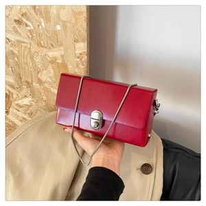 Close-up of wine red chain bag featuring silver metal twist lock and matte leather finish