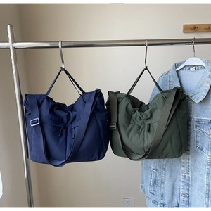 Détail de sacs cabas en nylon bleu marine et vert olive avec larges bandoulières réglables