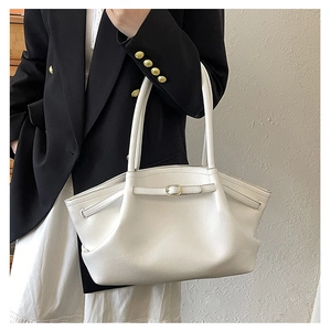 Close-up of white leather tote bag featuring pleated texture and gold buckle detail