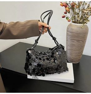 Close-up of black sequined underarm bag with knotted rope strap and metal zipper