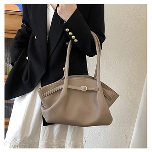 Close-up of khaki tote bag with winged design and fine buckle strap detail
