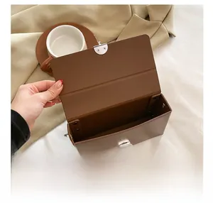 Detail showing internal compartment of a brown crossbody box bag with metal buckle