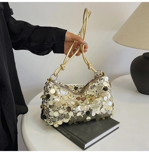Close-up of golden sequins on a crescent-shaped handbag with a knotted metallic chain strap
