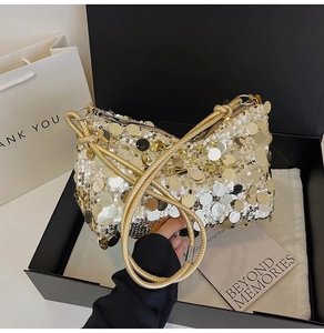 Detail view of sparkly sequin shoulder bag with golden rope strap inside a premium gift box