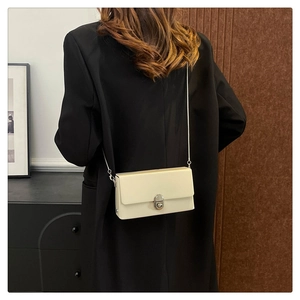 Chic cream leather square bag shown on model with silver chain strap and metal clasp
