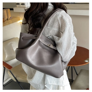 Detail of dark gray leather tote bag featuring adjustable side straps and soft texture