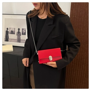 Detail of red patent leather shoulder bag with silver chain strap and metallic clasp