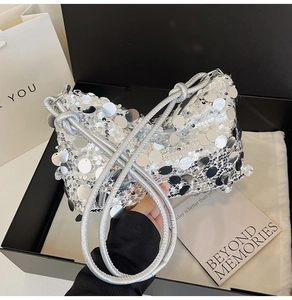Detailed view of silver sequin fabric and knotted braided shoulder strap on the bag
