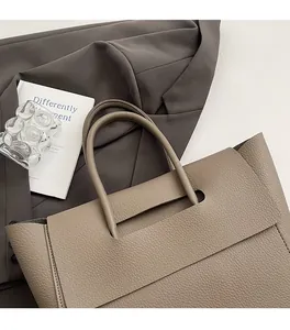 Detailed macro view of the lychee-textured taupe leather tote with cylindrical handles