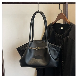 Detail of black pebbled leather tote bag with gold buckle strap and side wing design
