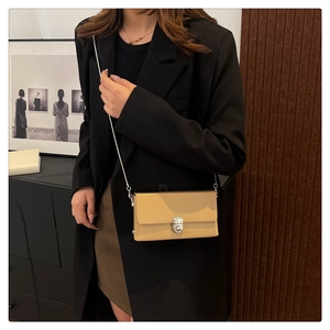 Brown crossbody box bag with silver lock and chain strap on a black blazer outfit