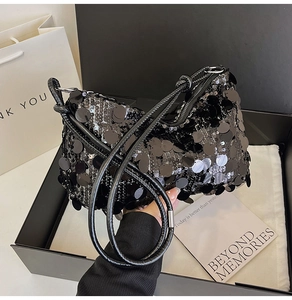 Detail of a chic black sequined shoulder bag presented in an elegant gift box set