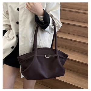 Detail of burgundy pebbled leather tote bag with gold buckle and curved edge