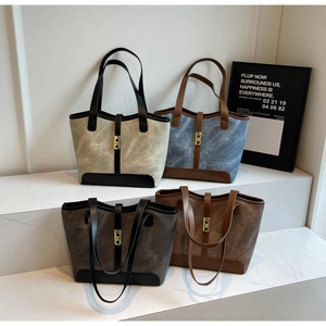 Détail de quatre sacs cabas minimalistes en beige, bleu, gris et marron avec boucles dorées