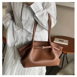 Detail of dark brown leather tote bag with silver buckle and textured pebble finish