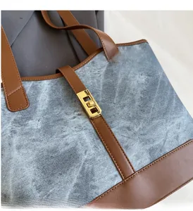 Détail du sac cabas en denim gris avec bordure en cuir marron et fermoir doré