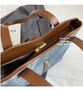 Détail du zip doré fluide et de la bordure en cuir marron sur le grand sac gris