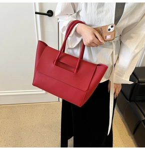 Macro detail of red lychee grain leather tote bag featuring structured flap closure