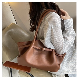 Close-up of brown pebbled leather tote bag with stylish buckle strap details
