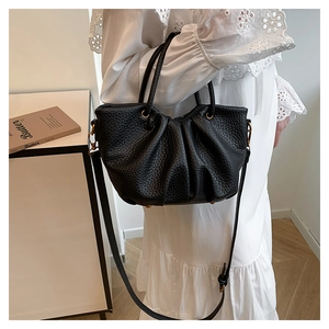 Détail du sac seau noir plissé avec texture litchi et finitions en métal doré