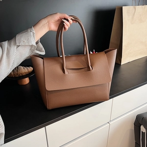 Detailed view of brown lychee texture leather tote bag with elegant flap design