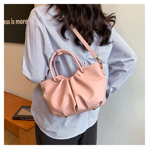 Détail du sac seau plissé rose montrant la texture grainée et la bandoulière réglable