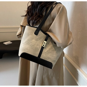 Détail du sac cabas en toile grise avec bordure en cuir noir et fermoir en métal doré