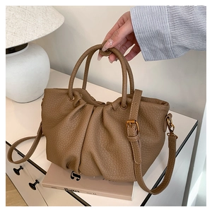 Détails des plis texturés et ferrures dorées sur un sac à main marron à motif litchi