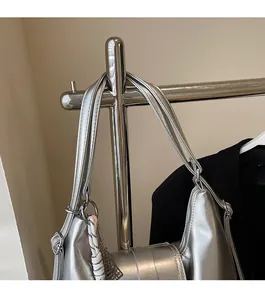 Détail d'un sac bandoulière en cuir argenté avec larges bretelles et décor tressé