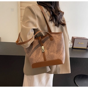 Détail d'un grand sac cabas en cuir marron avec fermoir métallique et doubles bandoulières
