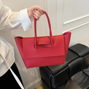 Detailed shot of a bright red lychee textured leather tote bag held in hand for daily commute