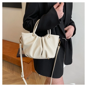 Détail d'un sac à main blanc plissé en cuir grainé avec boucles métalliques dorées
