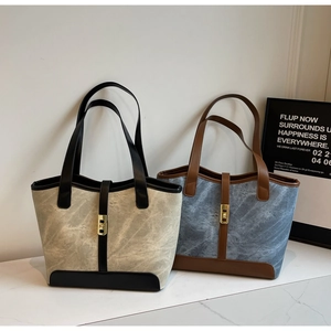 Détail de cabas en toile avec poignées en cuir et fermoirs rotatifs en métal doré