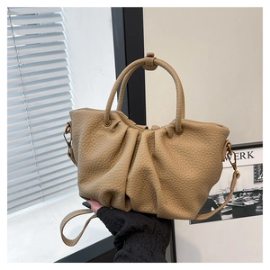 Détail du sac à main plissé beige en cuir texturé avec une poignée ronde élégante