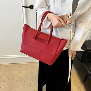 Detail of red lychee grain leather tote bag with unique handle attachment and stitching