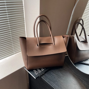 Top view of brown pebble leather tote bag on wooden table with elegant interior lighting