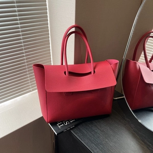 Close-up of red lychee grain leather texture and handle detail on a large tote bag