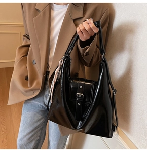 Gros plan d'un sac cabas en cuir noir brillant avec foulard décoratif et boucle en métal