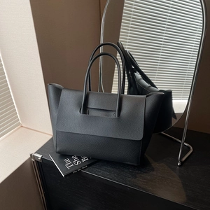 Detailed side view of black lychee grain leather tote bag with elegant flap design