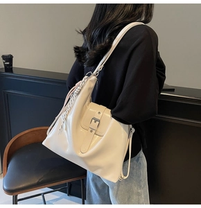 Détail du sac en cuir blanc cassé avec boucle vintage et bandoulière tissée élégante