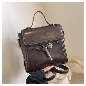 Detail of vintage dark brown faux leather bag with metal buckle and top handle