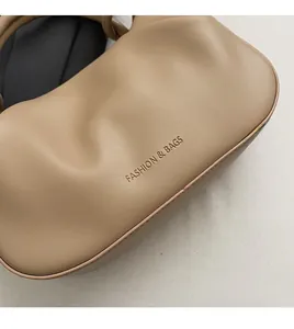 Detail shot of pleated soft leather texture and embossed FASHION & BAGS logo on the beige bag