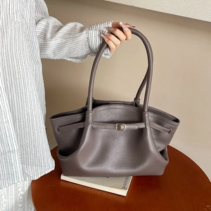 Large dark grey leather tote bag with pleated texture and adjustable strap on wood table