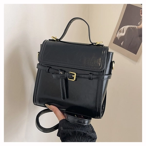Detailed close-up of a black retro square bag featuring golden buckle and top handle strap