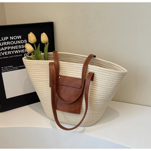 Detail of summer straw tote with brown leather pocket and handles in a stylish setting