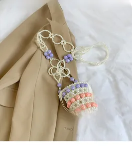Détail de la chaîne tissée main avec perles blanches et fleurs en résine colorées
